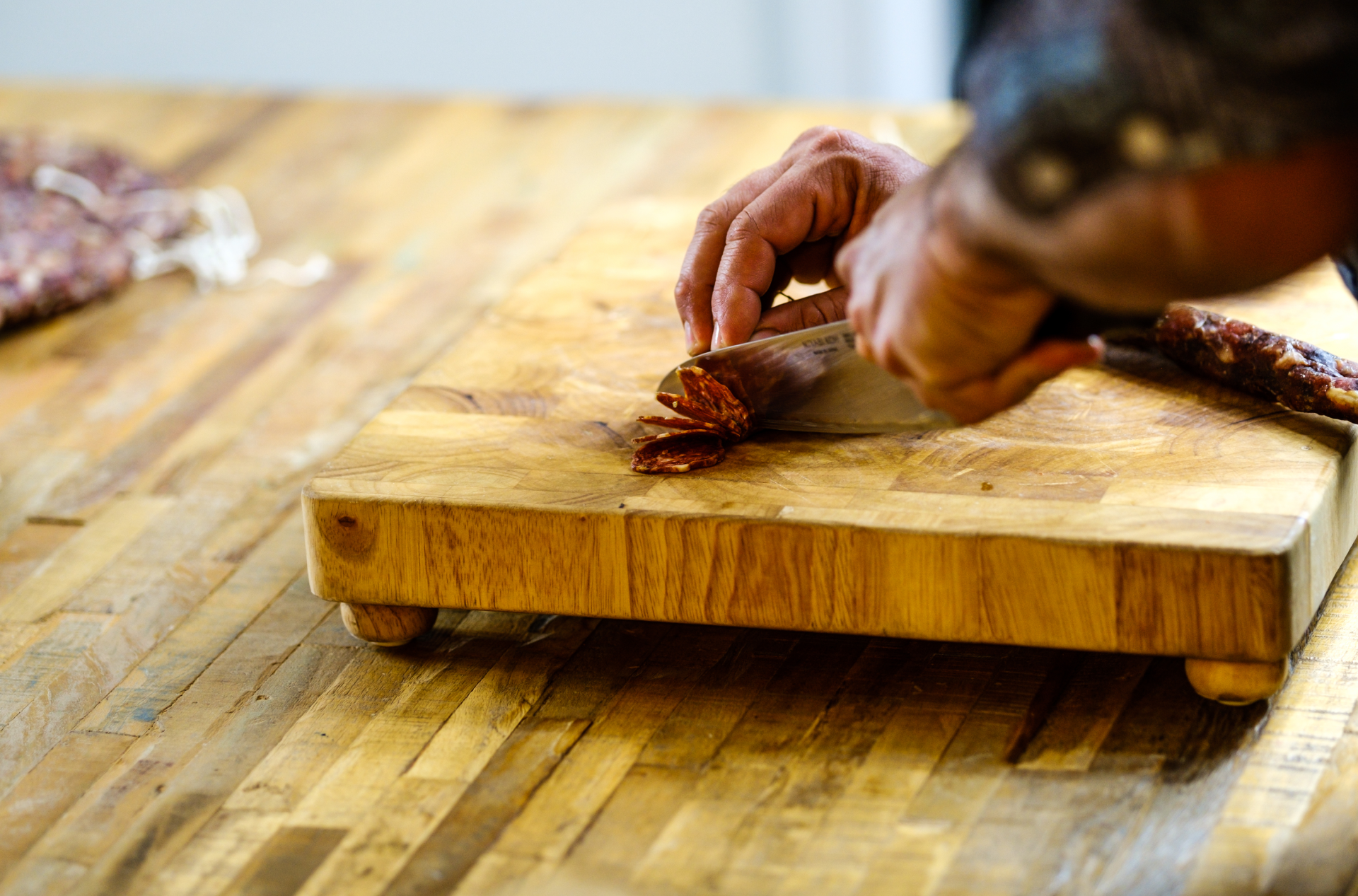 Salami being sliced on a wooden chopping board